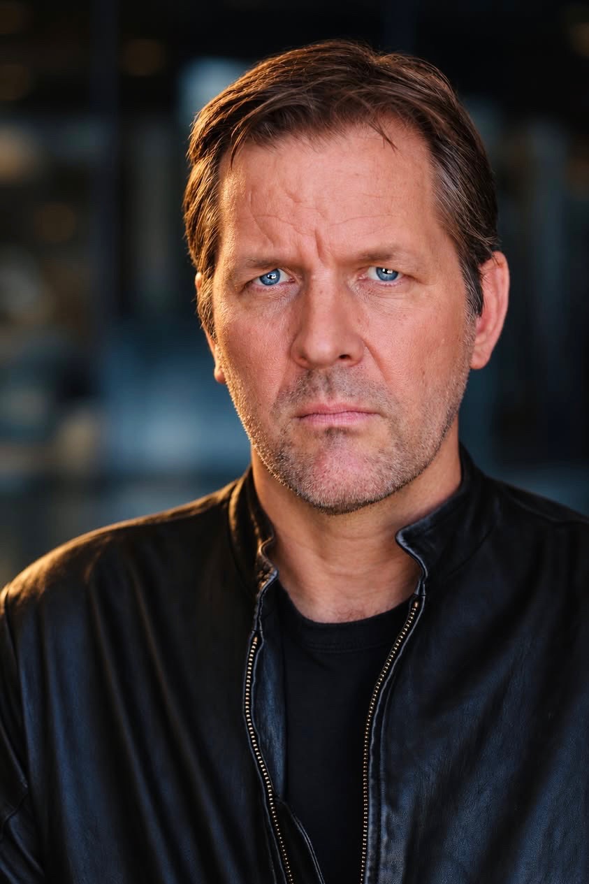 Erik Kins headshot in a black leather jacket